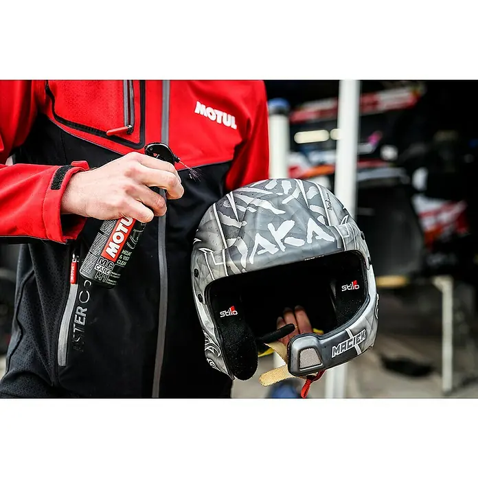 Limpiador específico para casco M1 y M2 - 500 ml, Apto para: Cascos de motocicleta - Un hombre limpia un casco de carreras Stilo gris con el limpiador de cascos y viseras de Motul. El producto garantiza una visión clara.