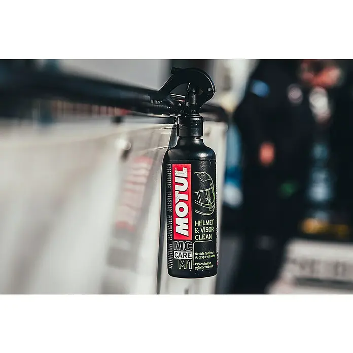 Limpiador específico para casco M1 - 250 ml, Apto para: Cascos de motocicleta - Una botella de limpiador de cascos y viseras Motul colgada de una barra, ideal para el mantenimiento de cascos y viseras de moto.