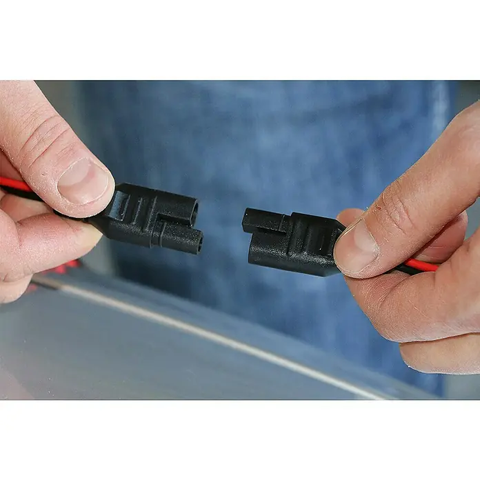Black+Decker Arrancador de baterías - Capacidad: 70 Ah, 12 V - Conectores eléctricos negros sujetados con las manos listos para conectarse. El diseño garantiza una conexión eléctrica segura y fiable.