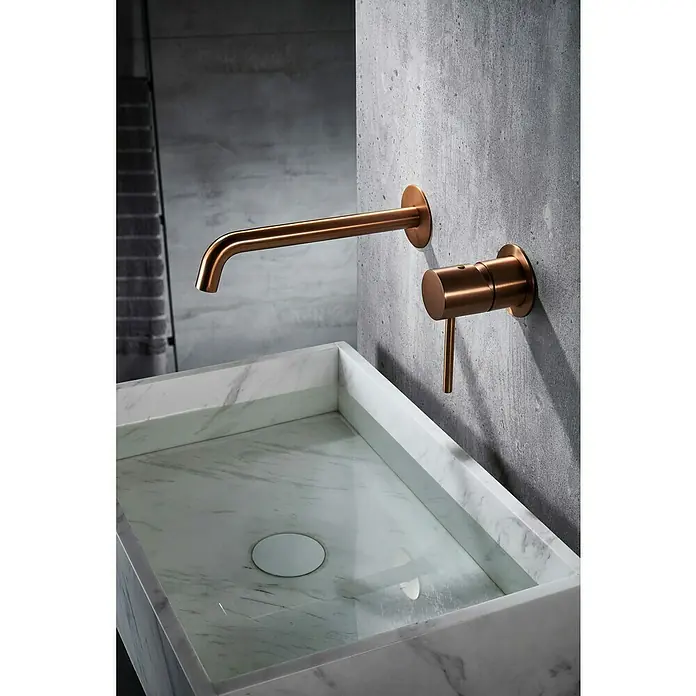 Camargue Natur Grifo de lavabo empotrado - Oro rosa - Elegante grifo de cobre en una pared de hormigón sobre un elegante lavabo de mármol.