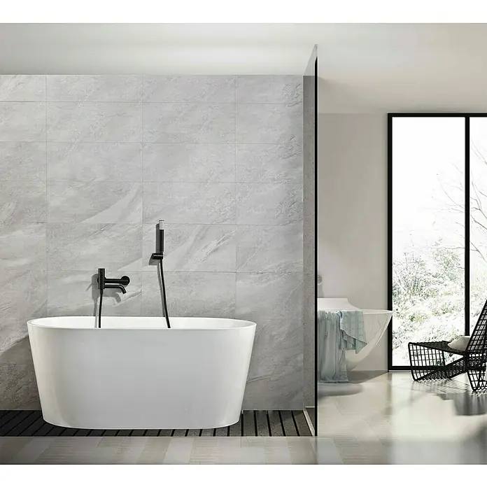 Camargue Natur Grifo monomando de bañera / ducha - Negro, Mate - Bañera exenta con grifo negro frente a pared de piedra gris en baño moderno y minimalista.