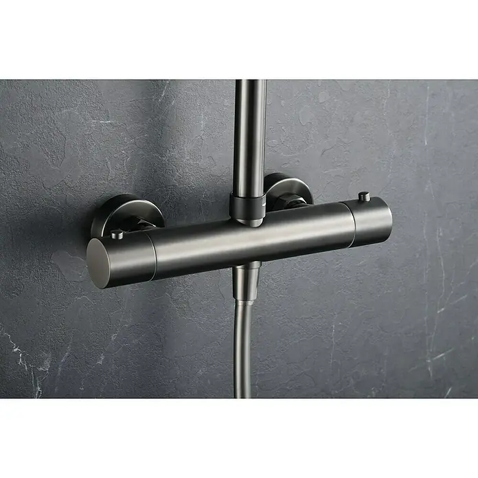 Camargue Natur Sistema de ducha - Con grifo termostático, Black gun metal - Una moderna válvula de ducha termostática de níquel cepillado está montada en una pared gris. La válvula tiene un diseño cilíndrico y minimalista.