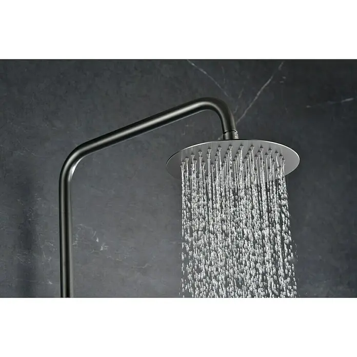 Camargue Natur Sistema de ducha - Con grifo termostático, Black gun metal - Primer plano de un elegante cabezal de ducha redondo con agua en cascada, destacando un ambiente de baño moderno.