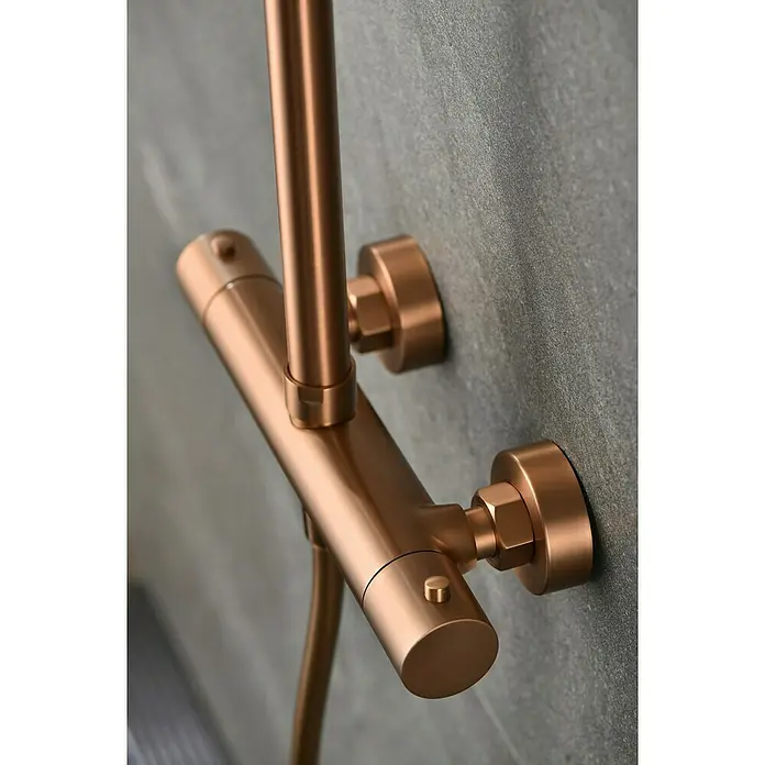 Camargue Natur Sistema de ducha - Con grifo termostático, Oro rosa - Primer plano de un elegante y moderno accesorio de ducha con acabado de cobre montado en una pared gris. Diseño elegante para cualquier baño.