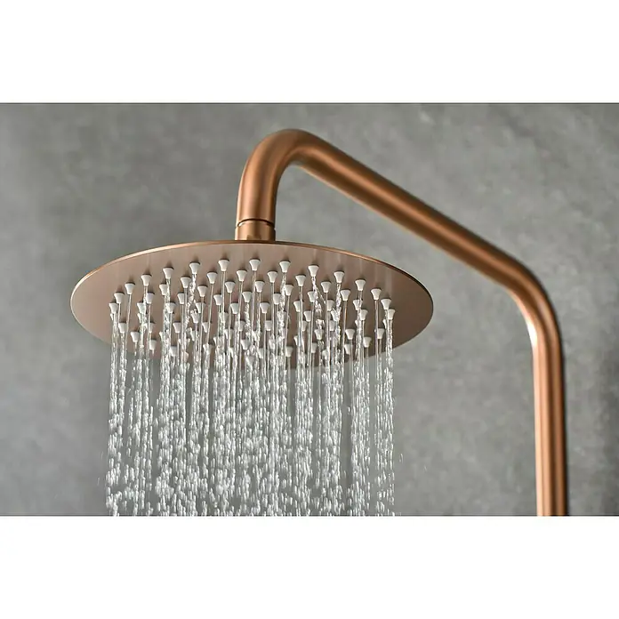 Camargue Natur Sistema de ducha - Con grifo termostático, Oro rosa - Primer plano de un moderno cabezal de ducha redondo en oro rosa con agua que fluye suavemente para una experiencia relajante.