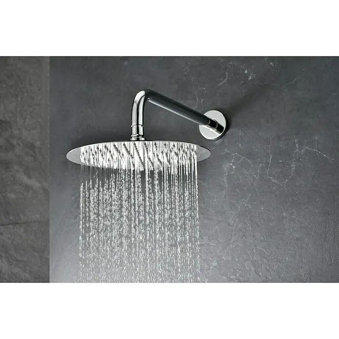 Camargue Natur Sistema de ducha empotrado - Con grifo termostático, Cromo - Primer plano de un moderno cabezal de ducha liberando chorros de agua, montado en una pared gris texturizada. Diseño de baño elegante.