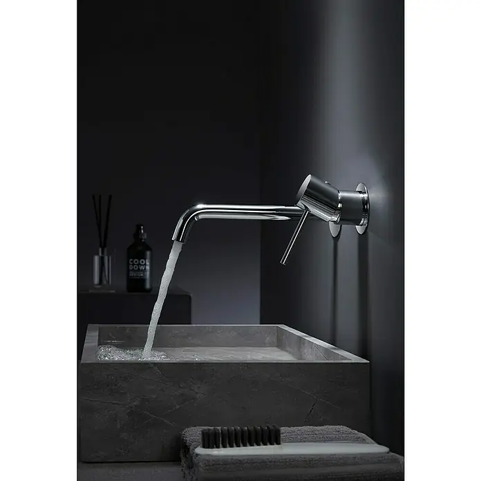 Camargue Natur Grifo de lavabo - Cromo, Brillante - Moderno grifo cromado en una pared oscura sobre un elegante lavabo cuadrado de piedra con agua fluyendo.