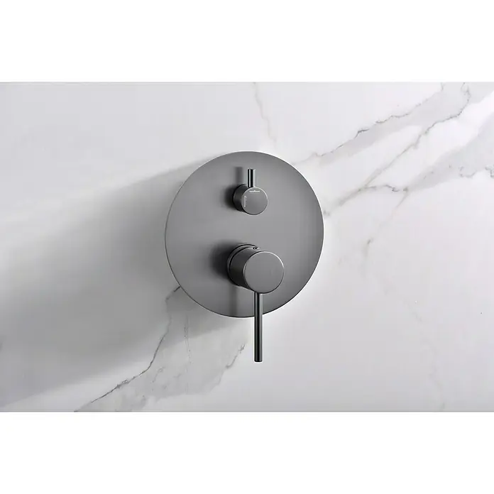 Camargue Natur Sistema de ducha empotrado - Con grifo monomando, Black Gum - Primer plano de un moderno termostato de ducha negro mate, redondo, con dos manijas, montado en una pared de mármol.