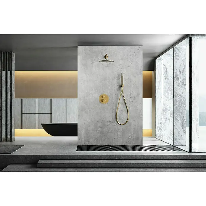 Camargue Natur Sistema de ducha empotrado - Con grifo termostático, Oro cepillado - Elegante baño con ducha de lluvia dorada y ducha de mano en una pared de concreto gris. Una bañera moderna y ventanas de mármol que irradian lujo.