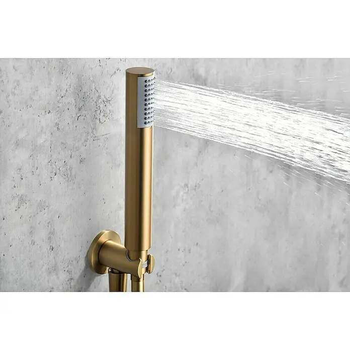Camargue Natur Sistema de ducha empotrado - Con grifo termostático, Oro cepillado - Primer plano de un moderno cabezal de ducha dorado que rocía chorros de agua contra una pared texturizada. Diseño de baño elegante.