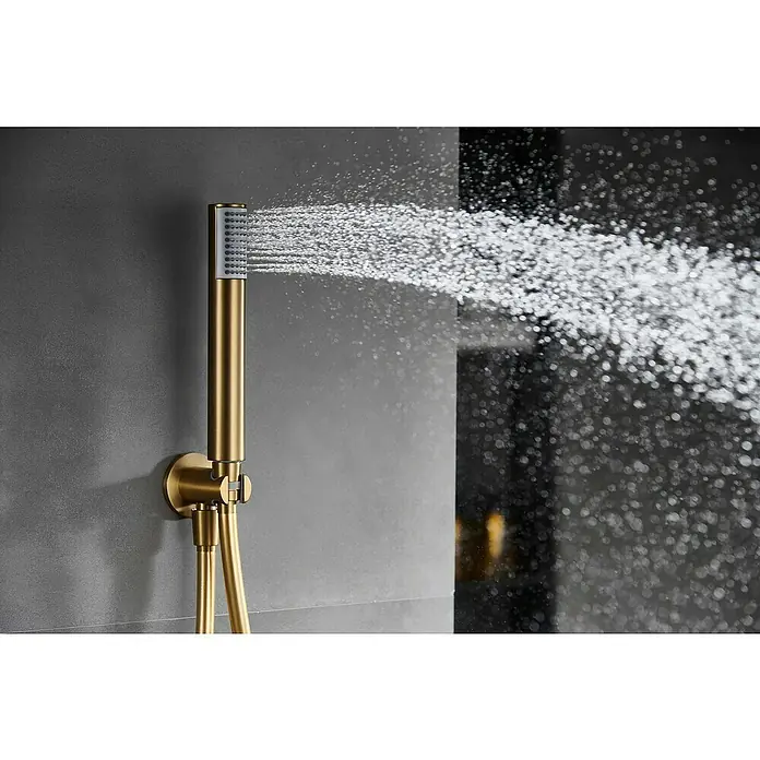 Camargue Natur Sistema de ducha empotrado - Con grifo monomando, Oro cepillado - Primer plano de un cabezal de ducha dorado rociando agua, montado en una pared gris.