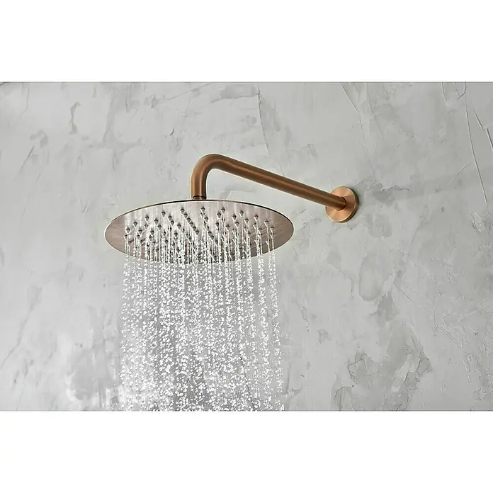 Camargue Natur Sistema de ducha empotrado - Con grifo monomando, Oro Rosa - Primer plano de un cabezal de ducha redondo con agua corriendo, montado en una pared gris. Muestra un diseño moderno y elegante.