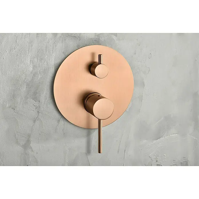 Camargue Natur Sistema de ducha empotrado - Con grifo monomando, Oro Rosa - Primer plano de un moderno accesorio de ducha redondo de oro rosa sobre una pared gris. Diseño elegante para baños.