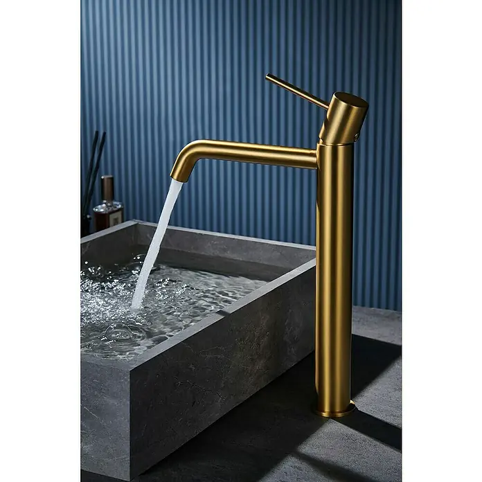 Camargue Natur Grifo de lavabo alto - Oro - Elegante grifo dorado sobre un lavabo de piedra gris. El diseño moderno se acentúa con el agua que fluye, dando estilo al baño.