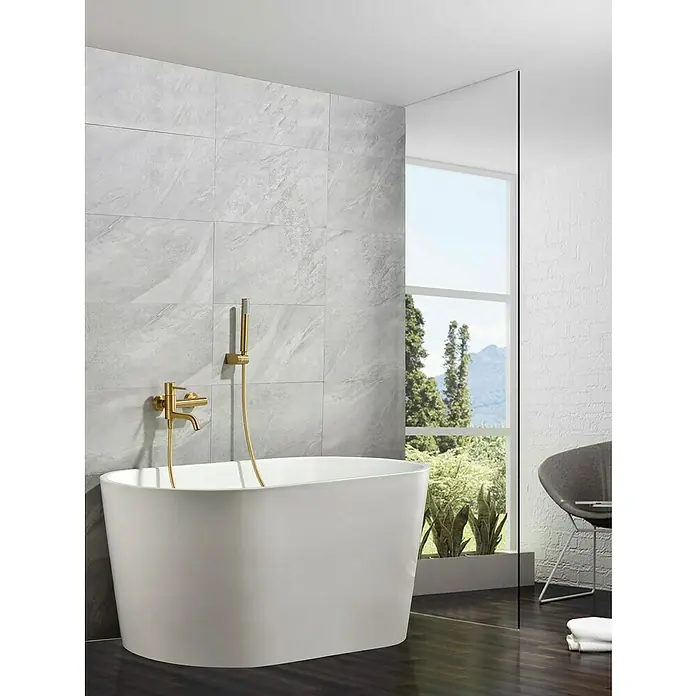 Camargue Natur Grifo monomando de bañera / ducha - Oro - Bañera exenta en un baño moderno con azulejos grises y accesorios dorados. Diseño elegante para momentos de relajación.