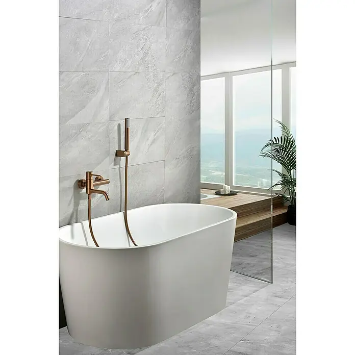 Camargue Natur Grifo monomando de bañera / ducha - Oro rosa - Bañera exenta con grifería en un baño elegante. Azulejos grises y mucha luz natural crean un ambiente relajante.
