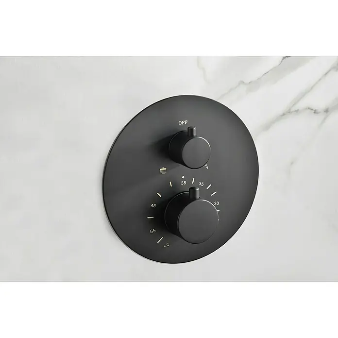 Camargue Natur Sistema de ducha empotrado - Con grifo termostático, Negro - Primer plano de un termostato de ducha redondo negro mate con control de temperatura e interruptor de encendido/apagado separado montado en una pared de mármol.