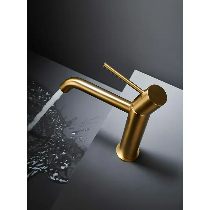 Camargue Natur Grifo de lavabo - Oro - Primer plano de un grifo dorado con agua fluyendo sobre una superficie gris.