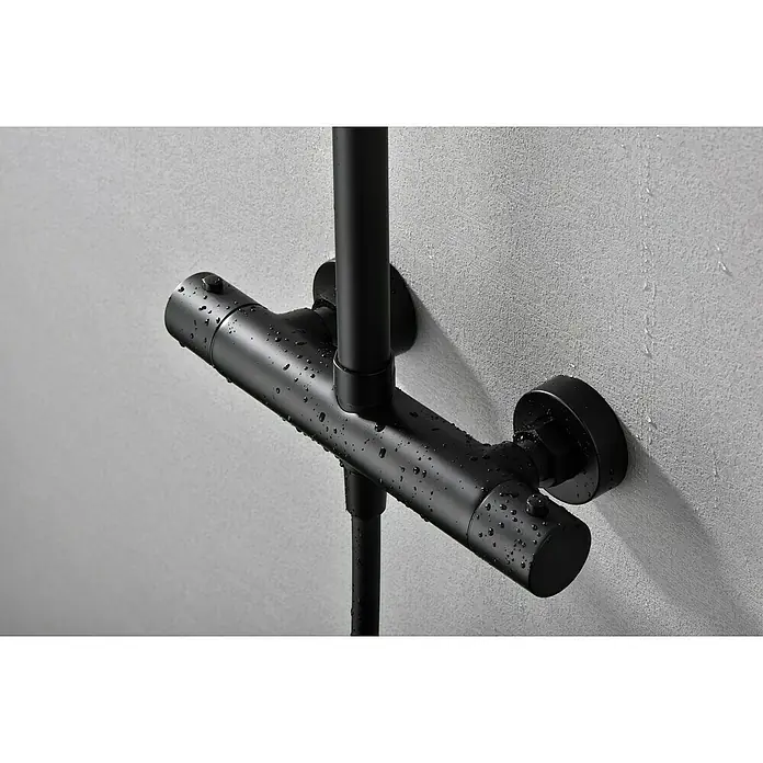 Camargue Natur Sistema de ducha - Con grifo termostático, Negro - Grifo de ducha negro con gotas de agua visibles sobre una pared gris. Diseño elegante de baño con grifo moderno y aspecto minimalista.
