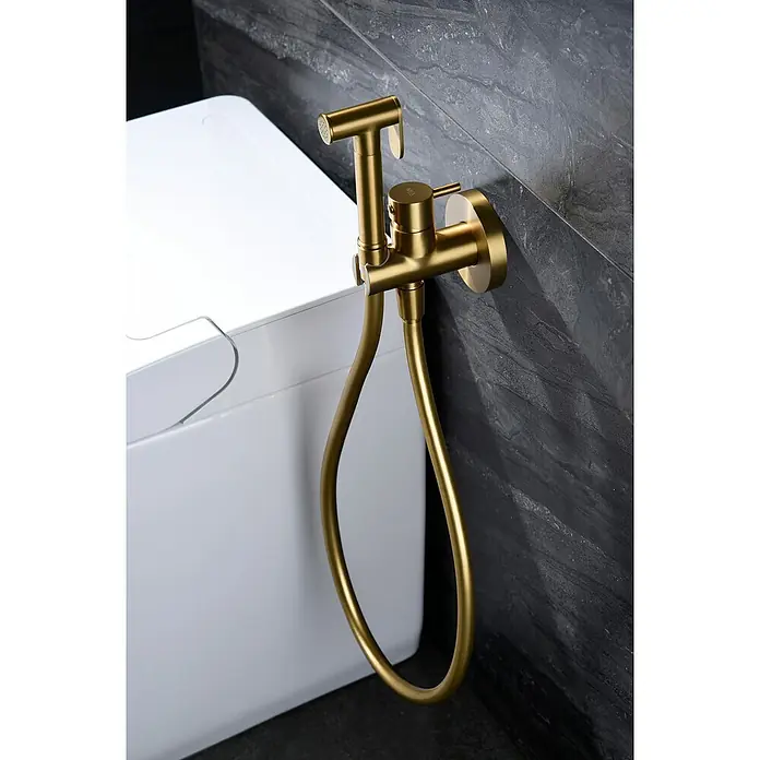 Camargue Natur Ducha higiénica inodoro - Oro - Kit de rociador de bidé dorado para higiene personal, elegantemente montado en una pared junto a un inodoro blanco.
