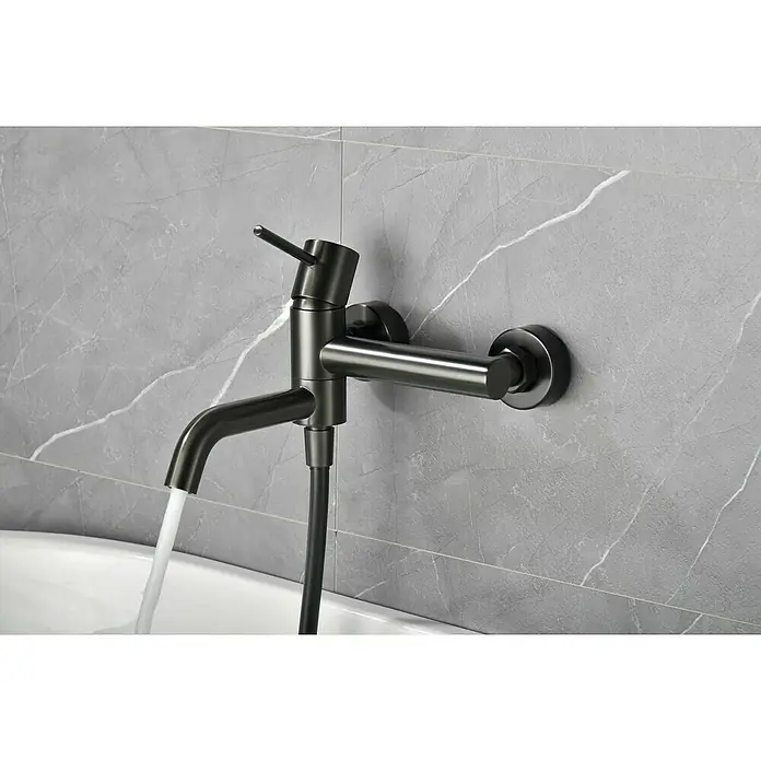 Camargue Natur Grifo monomando de bañera / ducha - Black gun metal - Primer plano de un moderno grifo de baño negro mate con agua corriente, sobre una pared de mármol gris.
