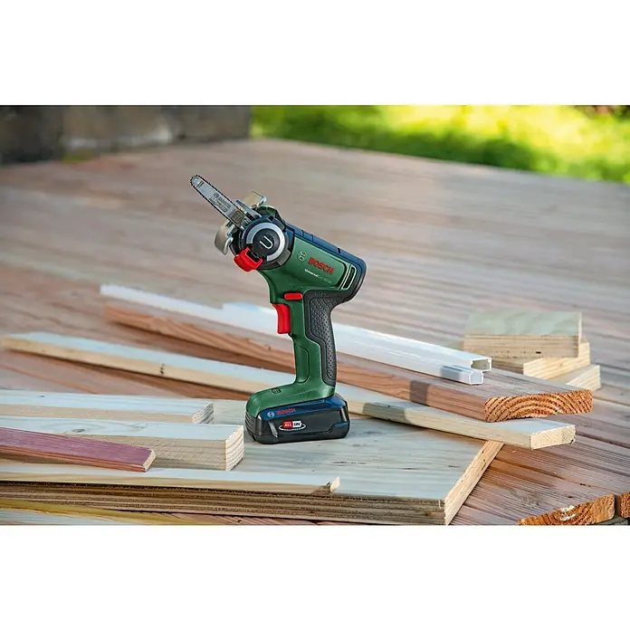 Bosch Power for All 18V NanoBlade-Säge Universal Cut 18V-65 - 18 V, 1 Akku, 2,5 Ah, 0 U/min - 8.000 U/min - Die Bosch Akku-Kettensäge UniversalChain 18V-20 mit diversen Holzstücken auf einer Holzoberfläche. Ein starkes Werkzeug für den Garten- und Baubereich.