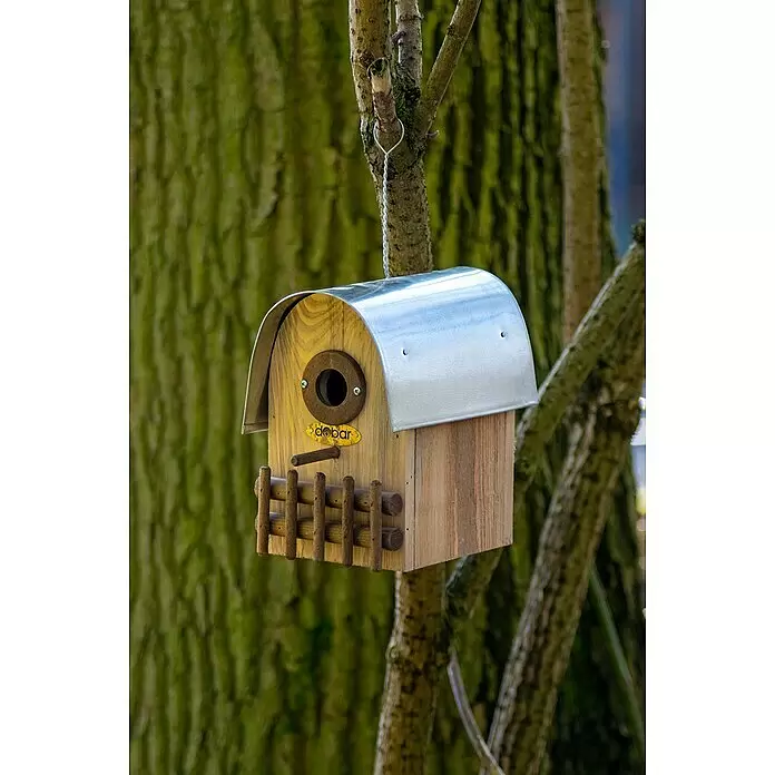 Dobar Nistkasten Rundhaus - 14 x 20 x 22 cm, Holz, Braun/Silber - Hölzernes Vogelhaus mit silbernem Metalldach, Einflugloch und kleinem Holzzaun, an einem Ast hängend.