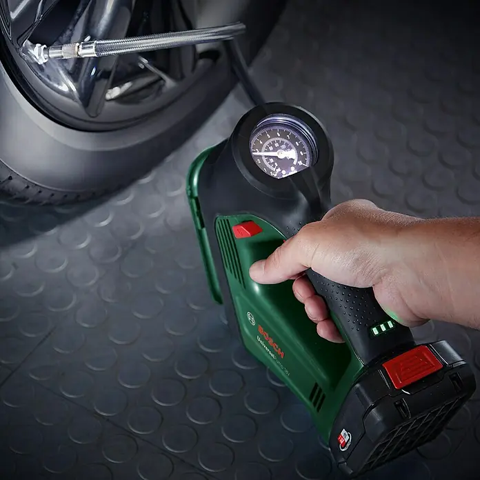 Bosch Power for All 18V Akku-Luftpumpe UniversalPump - 18 V, 1 Akku - Nahaufnahme einer Bosch UniversalPump 18V Akku-Luftpumpe, die an einem Autoreifen befestigt ist und den Reifendruck anzeigt.