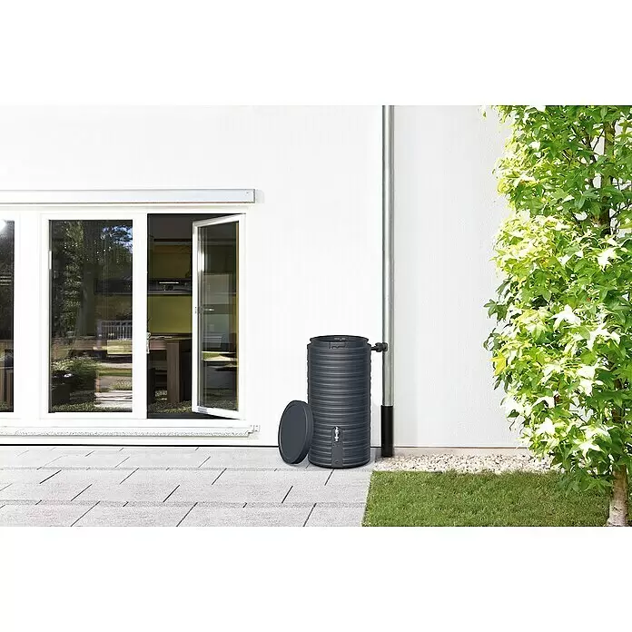 Garantia Classic Line Regenspeicher Nordic - 300 l, Graphite grey - Dunkelgraue, gerippte Regentonne steht an einer Hauswand und Fallrohr, ihr Deckel liegt daneben.