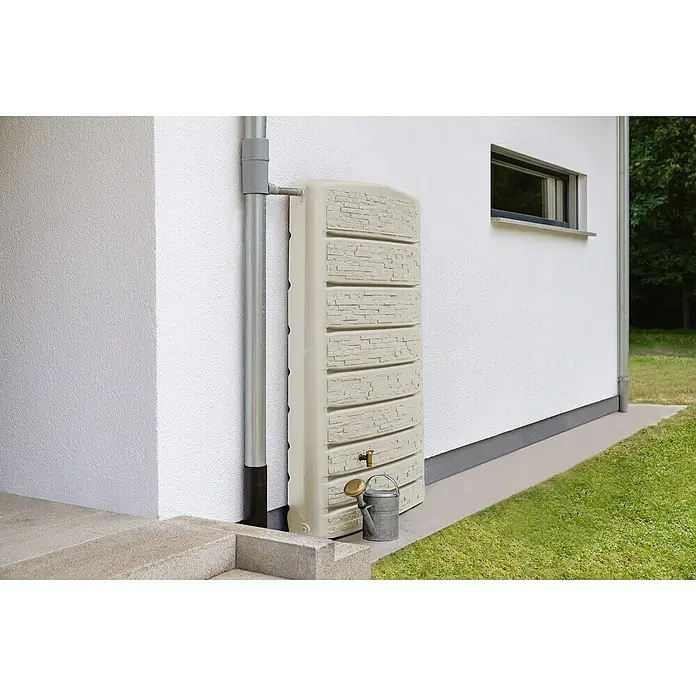 4rain Regenspeicher ExtraSlim Stone - 400 l, Beige - Ein Regentank in Steinoptik steht neben einem Fallrohr an einer Hauswand, mit einer kleinen Gießkanne davor. Praktische Wasserlösung.