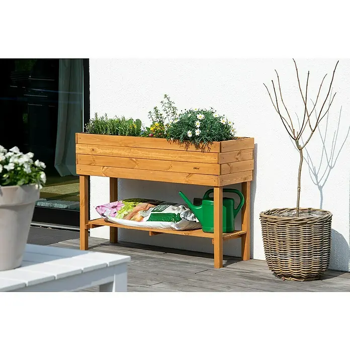Dobar Hochbeet - L x B x H: 117 x 40 x 80 cm, Holz, Braun - Hochbeet aus Holz mit Pflanzen und Gartenzubehör auf einer Terrasse. Das Beet steht auf einem Untergestell mit Ablage.