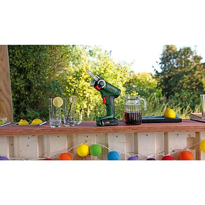 Bosch Power for All 18V NanoBlade-Säge Universal Cut 18V-65 - 18 V, 1 Akku, 2,5 Ah, 0 U/min - 8.000 U/min - Kompakte Bosch Akku-Kettensäge für müheloses Beschneiden, präsentiert auf einer sommerlichen Gartenbar. Perfekt für präzise Gartenarbeit.