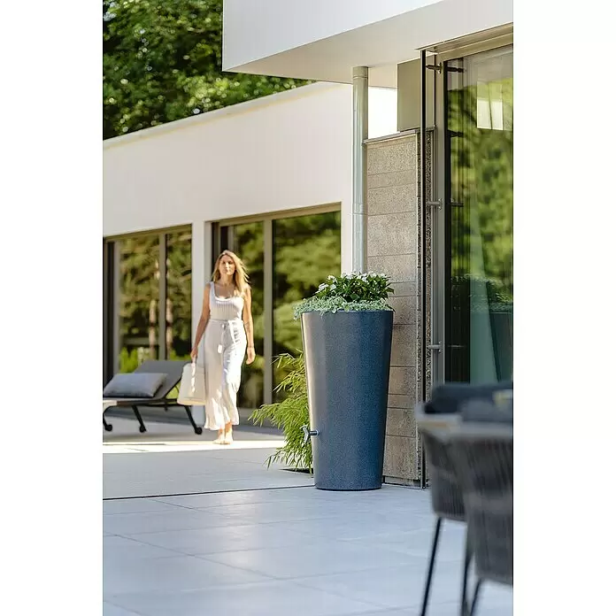 Garantia Modern Line Regenspeicher Stone 2 in 1 - 210 l, Lava - Hohes, dunkelgraues konisches Regenfass mit integriertem Pflanzgefäß und einem silbernen Zapfhahn, auf einer modernen Terrasse.