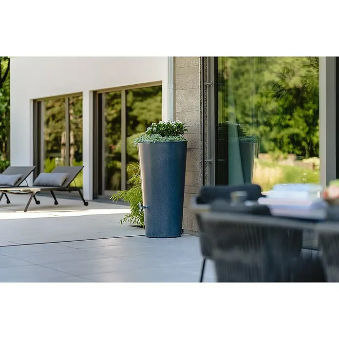 Garantia Modern Line Regenspeicher Stone 2 in 1 - 210 l, Lava - Ein schlanker, grauer Regenspeicher dient als Pflanzgefäß auf einer Terrasse. Das moderne Design integriert sich nahtlos in die Umgebung.