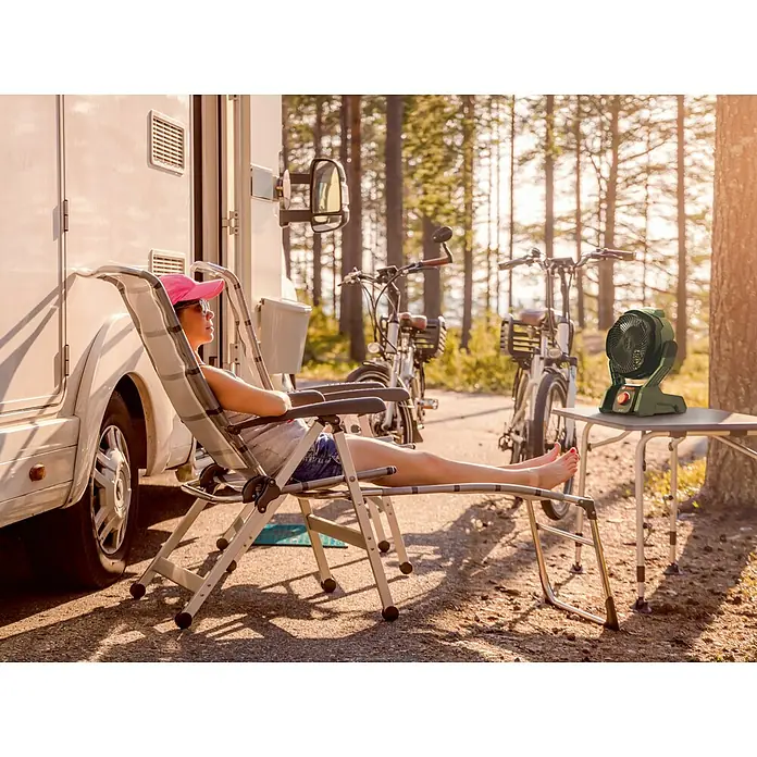 Bosch Power for All 18V Akku-Ventilator UniversalFan 18V-1000 - 18 V, 1 Akku, 2 Ah, Luftmenge: 1.000 m³/h - Entspannte Frau am Wohnmobil mit einem tragbaren Ventilator auf dem Tisch. Ideal für Campingausflüge und Outdoor-Aktivitäten.