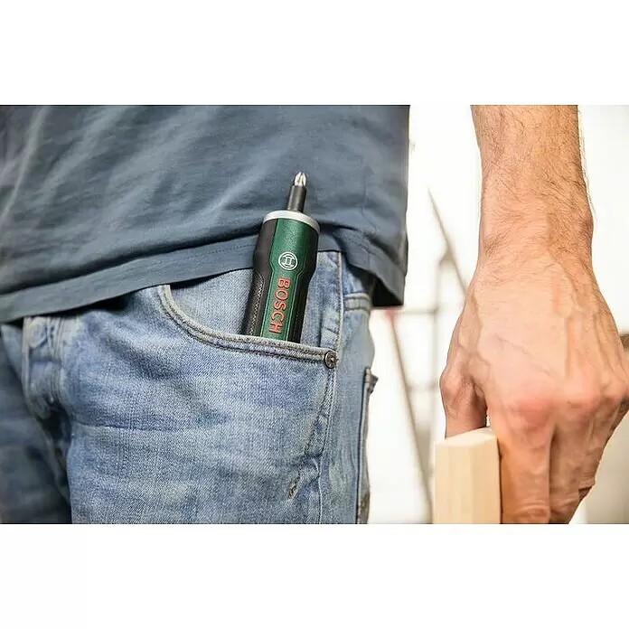 Bosch Akkuschrauber PushDrive - 3,6 V, 10 Schrauberbits - Ein schwarzer und grüner Bosch Akkuschrauber mit Bit, praktisch in der Vordertasche einer blauen Jeans.