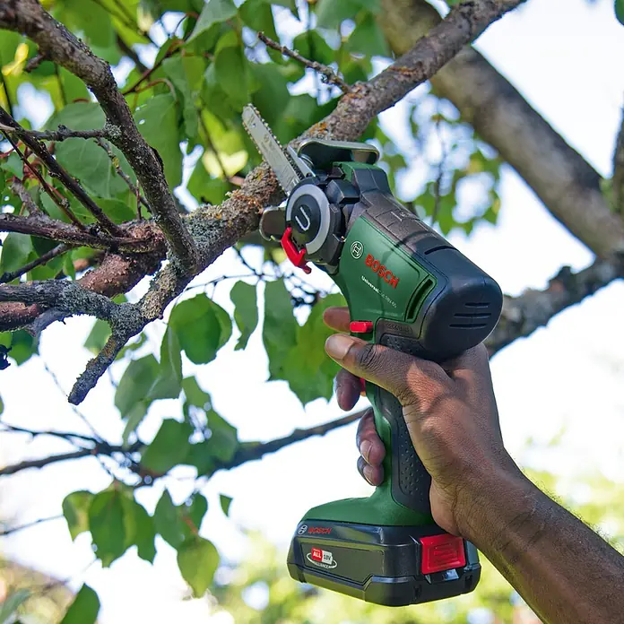 Bosch Power for All 18V NanoBlade-Säge Universal Cut 18V-65 - 18 V, 1 Akku, 2,5 Ah, 0 U/min - 8.000 U/min - Eine Akku-Astsäge von Bosch wird an einem Baumast verwendet, um diesen zu schneiden. Die Säge ist grün und schwarz und wird von einer Person bedient.
