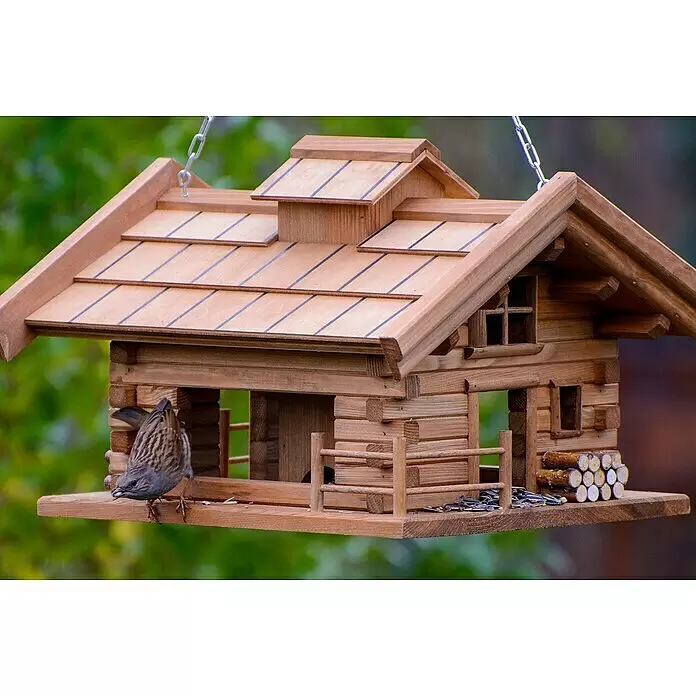 Dobar Vogelfutterhaus Appenzell - L x B x H: 37 x 37 x 26 cm, Braun, Holz - Detailliertes Vogelhaus aus Holz, geformt wie eine Blockhütte, hängend. Ein kleiner Vogel sitzt auf der Plattform und frisst Sonnenblumenkerne.