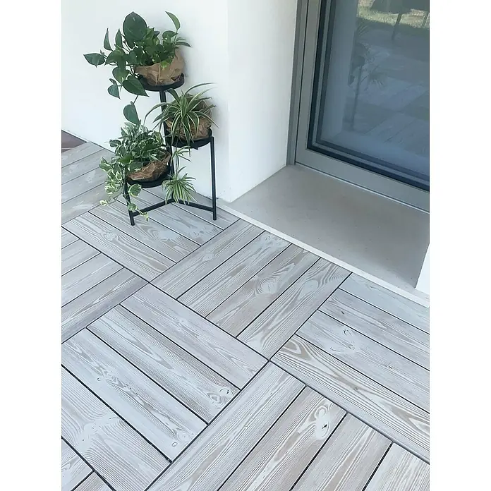 Klickfliese Smartdeck - Kiefer, 60 x 60 x 2,5 cm, Thermo White, 1 Stk. - Drei Zimmerpflanzen auf einem dekorativen Pflanzenständer auf einer Terrasse mit hellgrauen Holzbodenfliesen verlegt im Fischgrätmuster.