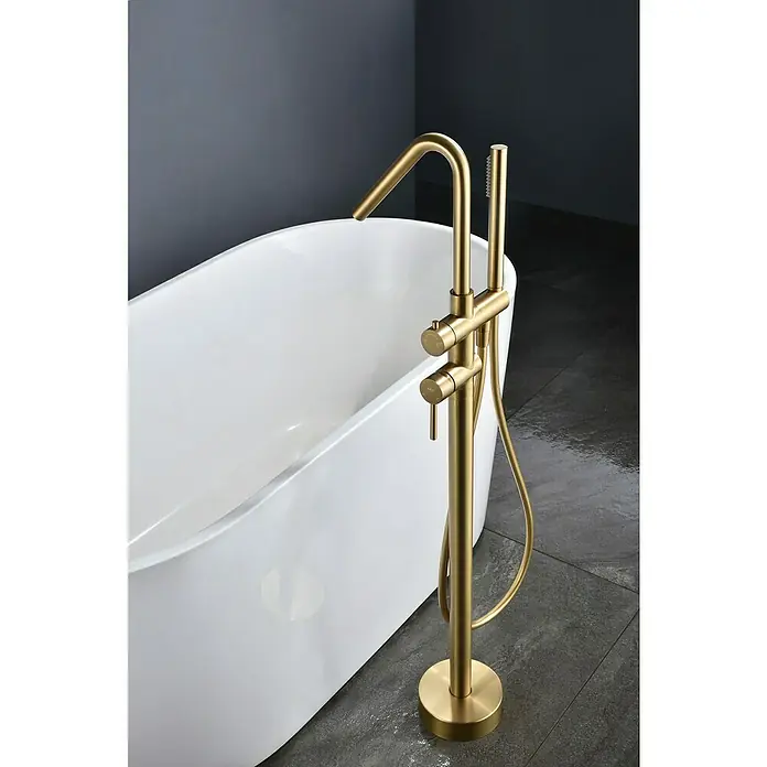 Camargue Natur Grifo para bañera - Oro - Grifo de bañera exento en tono dorado junto a una bañera blanca, crea un ambiente de baño lujoso.