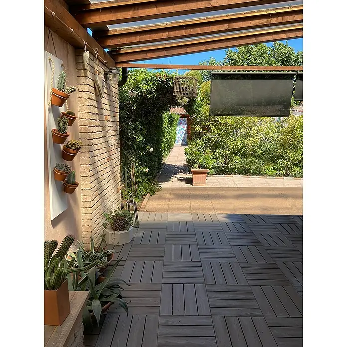 Klickfliese Snapwood - Polyethylen, 38 x 38 x 2,5 cm, Cappuccino Braun, 1 Stk. - Ein sonniger Außenbereich mit Holzfliesen, Kaktusdekorationen und einer grünen Pergola, die einen einladenden und natürlichen Charme versprüht.