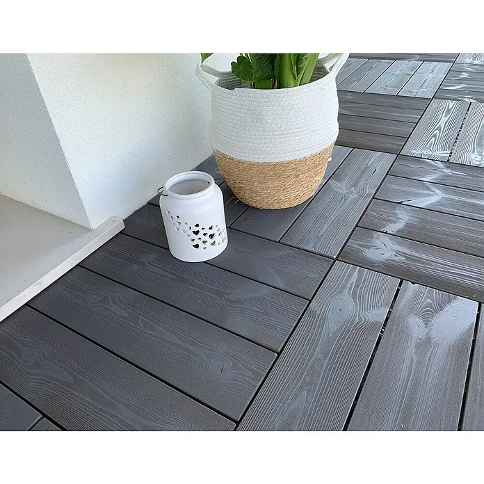 Klickfliese Smartdeck - Kiefer, 60 x 60 x 2,5 cm, Thermo Grey, 1 Stk. - Eine weiße Laterne mit Herzmuster und ein Korb mit Pflanze auf einem grauen Holzboden.