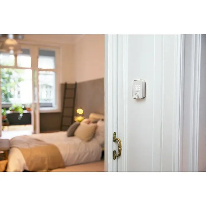 Bosch Smart Home Raumthermostat II - Weiß, Silber, L x B x H: 87 x 86 x 35 mm - Intelligenter Bosch-Thermostat an einer weißen Tür, der für eine effiziente Temperaturregelung sorgt.
