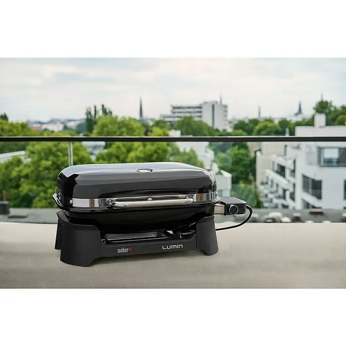 Weber Barbacoa eléctrica Lumin 2000 - Superficie de la parrilla (An x Pr): 49 x 33 cm, 2,2 kW, Negro - Primer plano de una parrilla eléctrica Weber Lumin en un balcón, perfecta para asar en la ciudad.