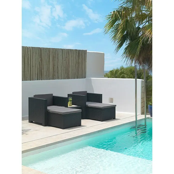 Shaf Conjunto de muebles Sira - 5 pzs., Polipropileno, Grafito - Dos tumbonas de jardín de ratán gris junto a la piscina bajo un cielo azul. Los modernos sillones invitan a relajarse al aire libre.