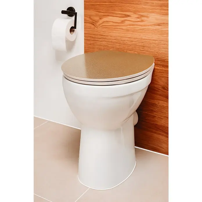 Poseidon WC-Sitz Golden Glitter - Duroplast, Gold/Weiß, Mit Absenkautomatik - Nahaufnahme einer modernen Toilette mit goldfarbenem Deckel, die sich an einer Wand mit Holzstruktur befindet, daneben Toilettenpapier.