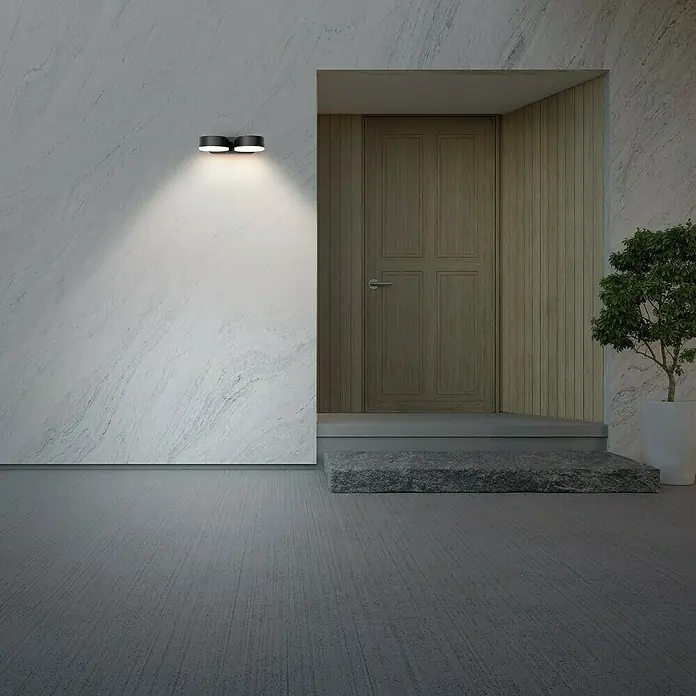 Forlight Pale Aplique exterior LED - 21 W, L x An x Al: 11 x 14 x 4 cm, Antracita, Blanco neutro - Luz exterior negra moderna ilumina una pared de mármol junto a una puerta de madera, añadiendo elegancia y estilo a la entrada.