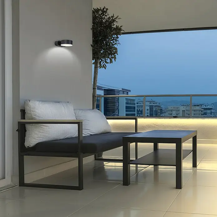 Forlight Pale Aplique exterior LED - 10,5 W, L x An x Al: 11 x 8,3 x 4 cm, Antracita, Blanco neutro - Toma exterior de un moderno foco de pared negro que ilumina una acogedora zona de estar en un balcón, creando un ambiente agradable.