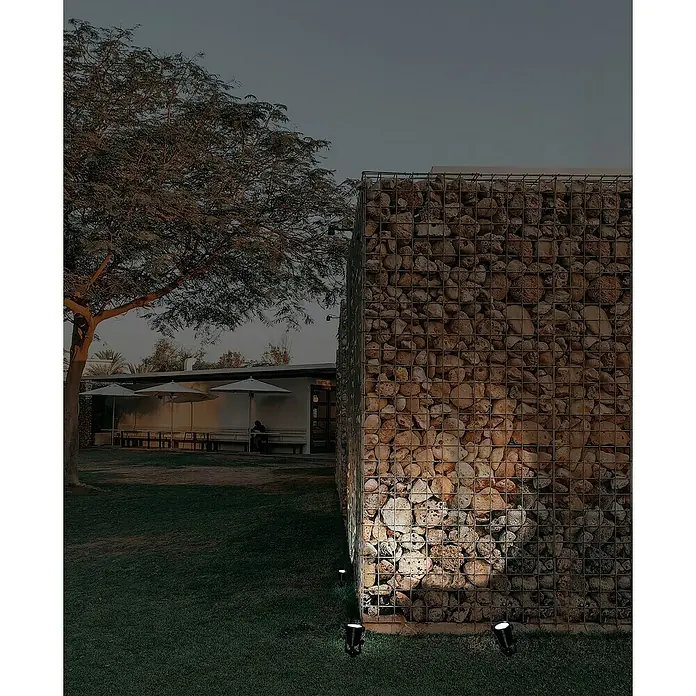 Forlight Proyector LED solar Hub - Blanco frío, IP65 - Muro de gaviones iluminado en un entorno exterior, combinando elemento arquitectónico con iluminación ambiental.