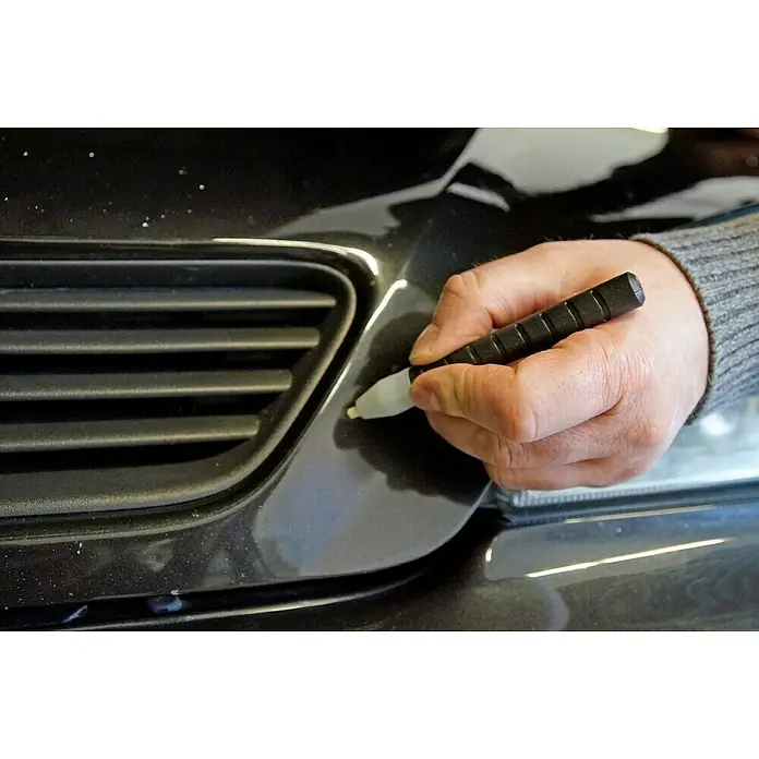 Presto Rost-Entferner - Einsatzbereich: Kfz-Bereich - Ein Mann repariert mit einem Lackstift einen kleinen Lackschaden an einem schwarzen Auto. Der Lackstift hat einen weißen Applikator.